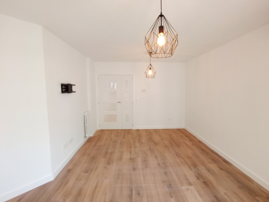 Salón reformado con lámparas de diseño y suelo de madera